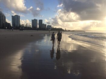 An Aussie couple walks barefoot at low tide along the Gold Coast just south of Brisbane. You can almost feel the sand squishing between your toes, eh mate?