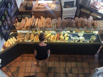 A middle-aged woman carefully ponders the baguettes and brioche at Paul Patisserie. So many carbs, so little time.